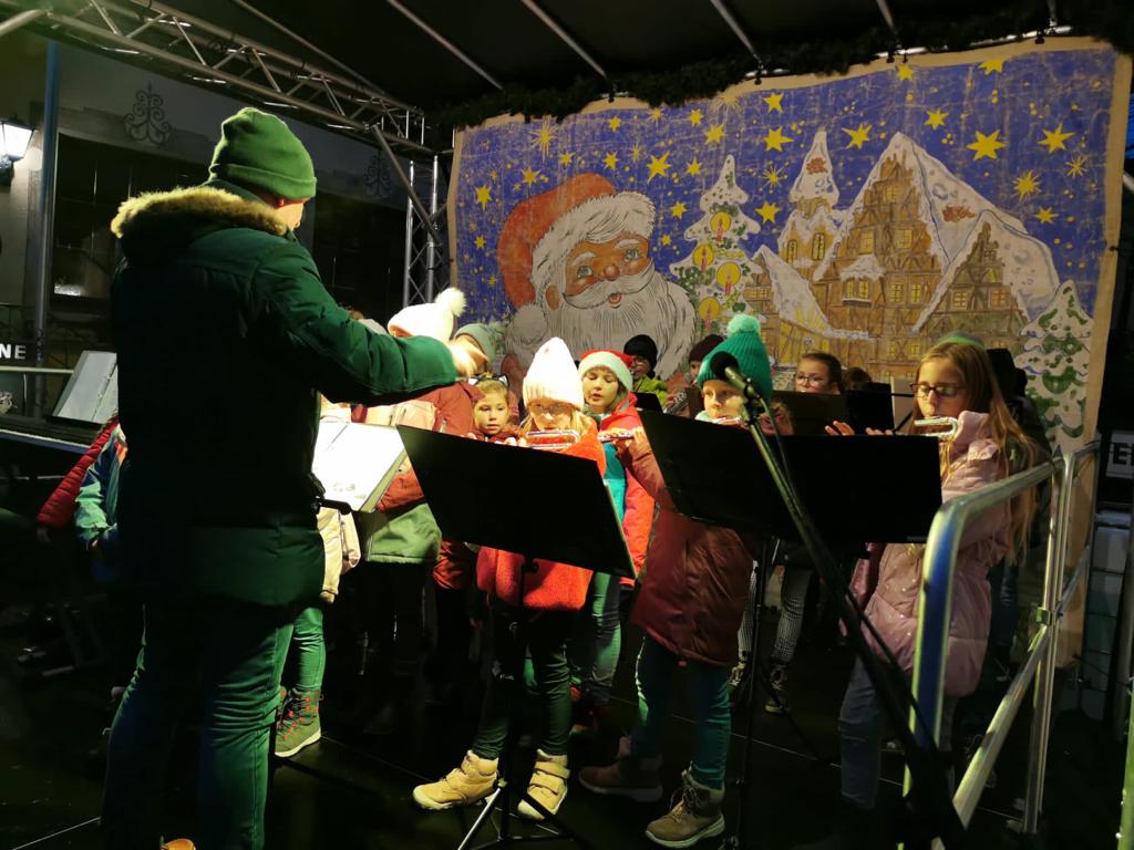 Stimmungsvolle Auftritte des Grundschulchors und der Bläserklasse beim Weihnachtsmarkt und dem musikalischen Weihnachtsdiabuch der Städtischen Mediothek (21.12.2022)